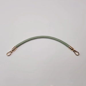 Detail of pea green PU leather bag strap with golden metal hooks on white background