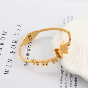 Detailed shot of golden butterfly bangle with matte finish and spring hinge clasp