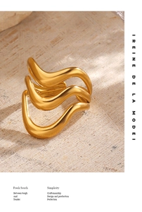 Detailed view of wide gold wave ring on textured stone background with elegant shadows