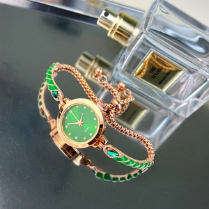 Detail of elegant gold quartz watch with green dial and matching enamel bracelet link
