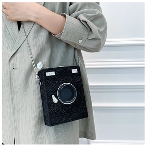 Detailed view of a black glitter camera-shaped crossbody bag with a silver chain strap