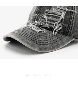 Macro detail of distressed ripped holes and stitching on washed grey denim baseball cap