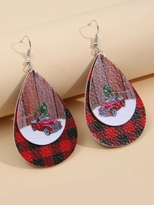 Close-up of teardrop leather earrings with red truck, Christmas tree, and plaid pattern