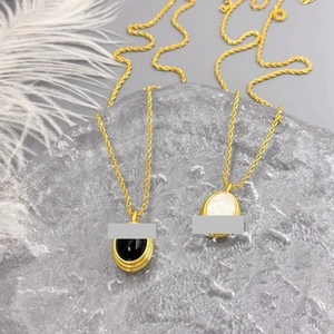 Detail shot of luxury oval pendant necklaces with black and white stones on ice texture