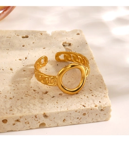 Detail shot of a golden hollow oval ring with chain texture on a beige stone stand
