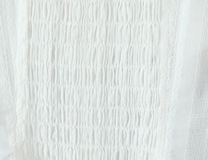 Detailed macro view of white lace fabric with sheer stripes and delicate pleated texture
