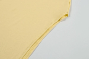 Detailed close-up of fine stitching and hem work on light yellow knit summer dress