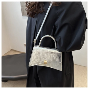Silver crocodile embossed crossbody bag with distinctive curved base and metal buckle