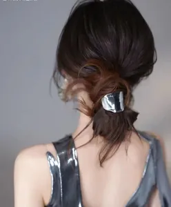Close-up of a silver liquid metal geometric hair clip styled on a low ponytail