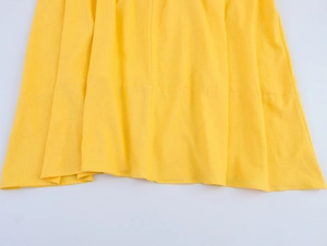 Detailed view of yellow linen-textured dress hem with clean stitching and soft pleats