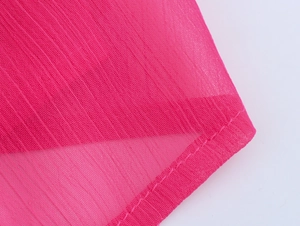 Vue détaillée du tissu en mousseline rose vif avec de délicats plis verticaux et bords