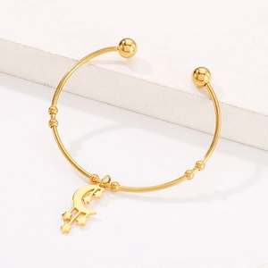 Close-up of golden moon and star charms on adjustable stainless steel bangle