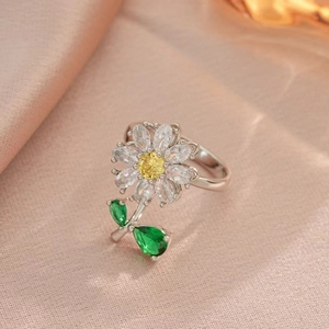 Macro shot of silver rotating sunflower ring with yellow and white crystals on pink silk
