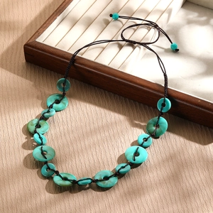 Detail of turquoise beaded necklace with adjustable brown cord on a wooden jewelry display