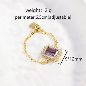 Macro shot of adjustable gold chain ring with a purple gemstone and white zircon stones