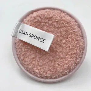 Macro detail of a soft pink microfiber face puff with a white Clean Sponge finger strap