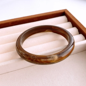 Detail of vintage acrylic bangle with amber smudge patterns in a white velvet jewelry box