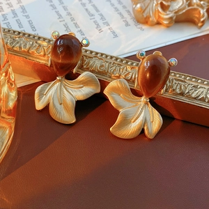 Macro detail of goldfish earring with brown teardrop gem and matte gold fish tail