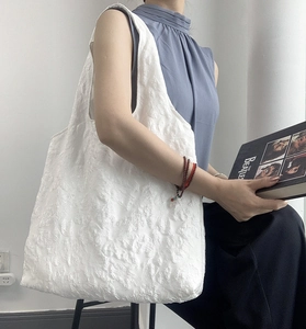Vue latérale du sac fourre-tout en jacquard blanc avec motifs floraux sur un modèle