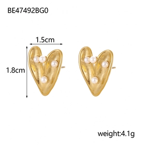 Detail shot of heart-shaped gold earrings with white pearl inlay, 1.5cm by 1.8cm size