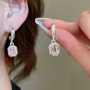 Macro shot of silver C-shape earrings with pink zircon stone and elegant metal frame