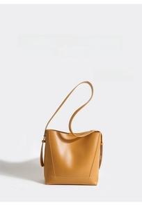 Detail of yellow minimalist bucket bag showing smooth leather texture and adjustable strap