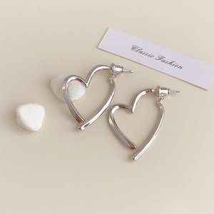 Detailed view of silver heart earrings with a polished finish on beige stones
