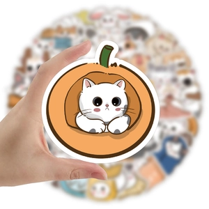 Close-up of a hand holding a round sticker featuring a cute white cat in a pumpkin