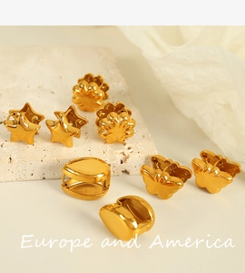 Group of gold butterfly and star earrings displayed on beige stone and white silk fabric