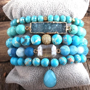 Detail of bohemian stackable bracelets featuring turquoise beads and crystal druzy charms