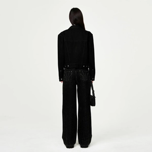 Vue de dos d'une femme portant une veste courte en jean noir et un pantalon large taille haute
