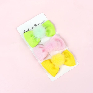 Three-piece set of velvet bow hair clips in green, pink, and yellow on display card