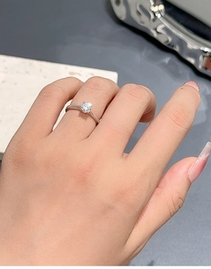 Close-up of a one carat moissanite silver ring with classic claw setting on a finger