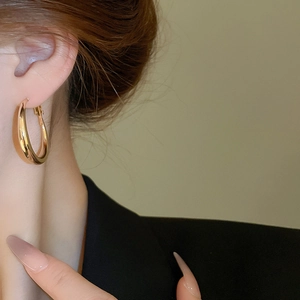 Detailed view of chunky teardrop gold hoop earrings on a model for minimalist style