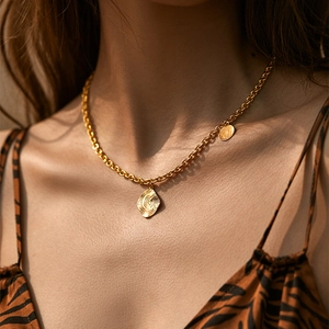 Elegant gold OL style necklace with teardrop swirl pendant on model in warm natural light