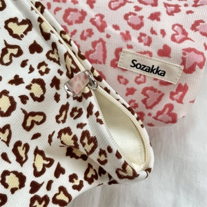 Close-up of corduroy leopard heart makeup bags with metal zippers and woven labels