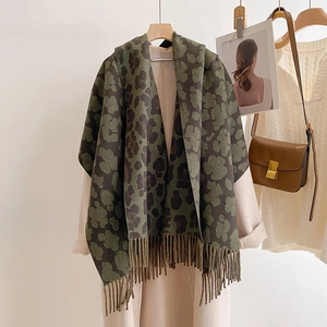 Detail of army green leopard print cashmere scarf with tassels on a hanger