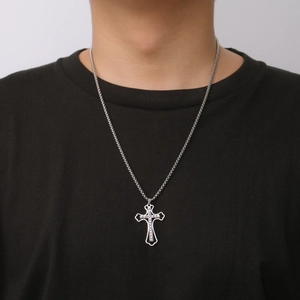 Close-up of a silver stainless steel cross pendant with cubic zirconia on a male model