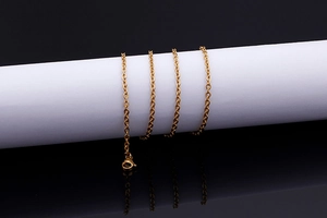 Macro shot of gold-plated titanium steel cable chain reflecting on a black mirror surface