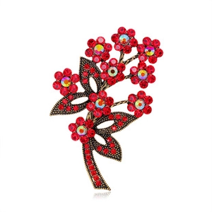 Macro detail of vintage floral brooch with red rhinestones and bronze alloy leaves