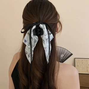 Detail of shark clip with black ribbon bow and white ink-wash printed silk streamers