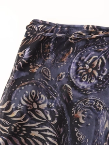 Détail du tissu en maille avec motifs floraux or et violet et texture fine