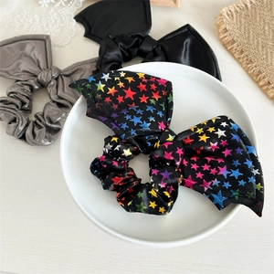 Three satin Halloween scrunchies with bat wings in black, gray, and rainbow star patterns