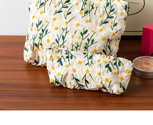 Detail of embroidered daisy floral canvas pouch set on a wooden surface backdrop
