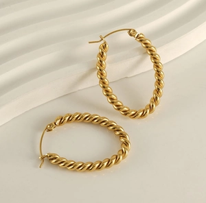 Macro detail of golden oval twisted hoop earrings with textured vintage spiral finish