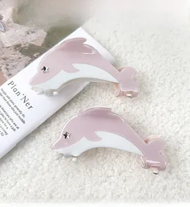 Detail of pink and white dolphin hair claws with star accents on soft plush background