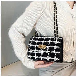 Lifestyle view of a black and white tweed crossbody bag with golden chain strap and lock