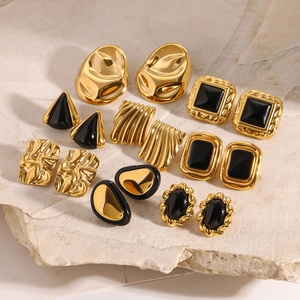 Vintage stainless steel earrings set in gold and black enamel on stone background