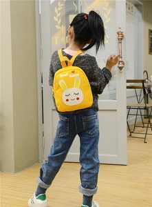 Close-up of a cute yellow cartoon rabbit backpack on a child with a heart pattern