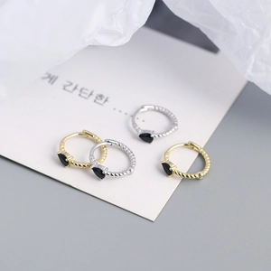 Macro detail of twisted S925 silver hoop earrings with black teardrop gemstone in gold and silver